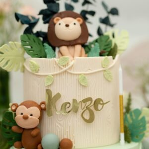 Adorable jungle-themed layer cake with lions and monkeys as decor, perfect for celebrations.
