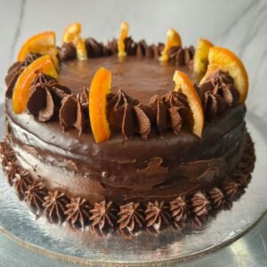 A rich chocolate cake topped with orange slices and chocolate frosting.