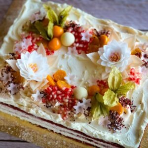 Beautifully decorated cake with floral and fruit toppings, perfect for celebrations.