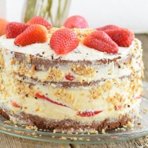 Delicious strawberry-layered cake with cream and nuts on a rustic wooden table. Perfect for dessert enthusiasts.