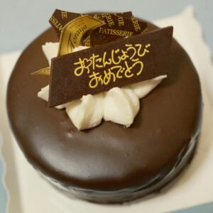 Delicious chocolate cake with creamy topping and a decorative sign in Japanese.