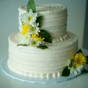 Beautiful minimalist wedding cake adorned with white and yellow flowers for a timeless celebration.