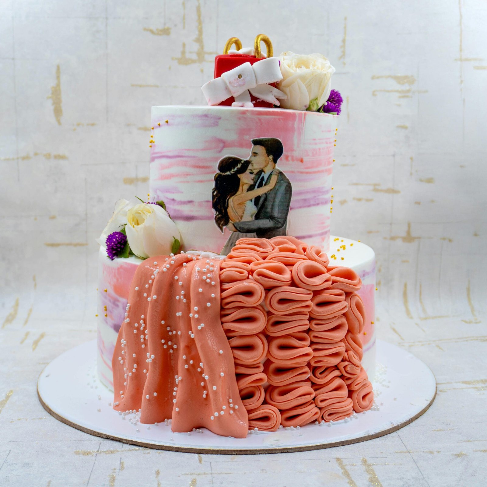 A beautifully decorated wedding cake featuring floral elements and a painted couple in embrace.