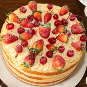 A mouth-watering layered cake topped with fresh strawberries and cherries, perfect for celebrations.